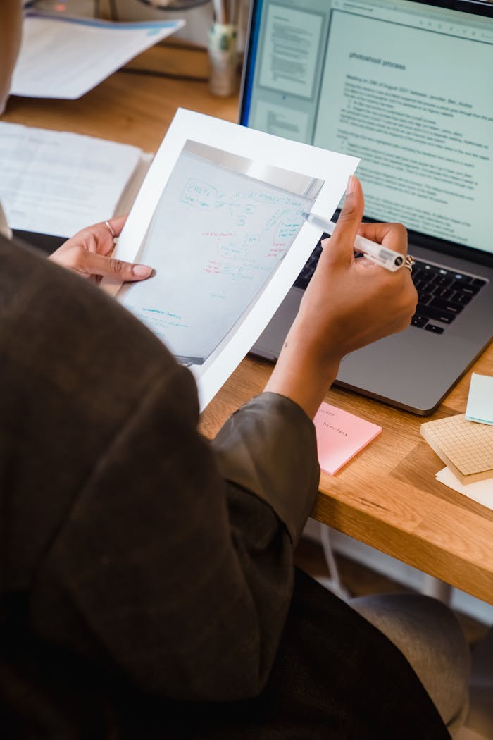 why-choose-us Woman reviewing printed documents at a desk with laptop, workspace tools visible.